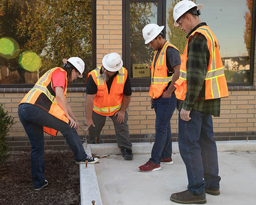 A group of building inspection technology students and an instructor inspecting a poured building foundation.